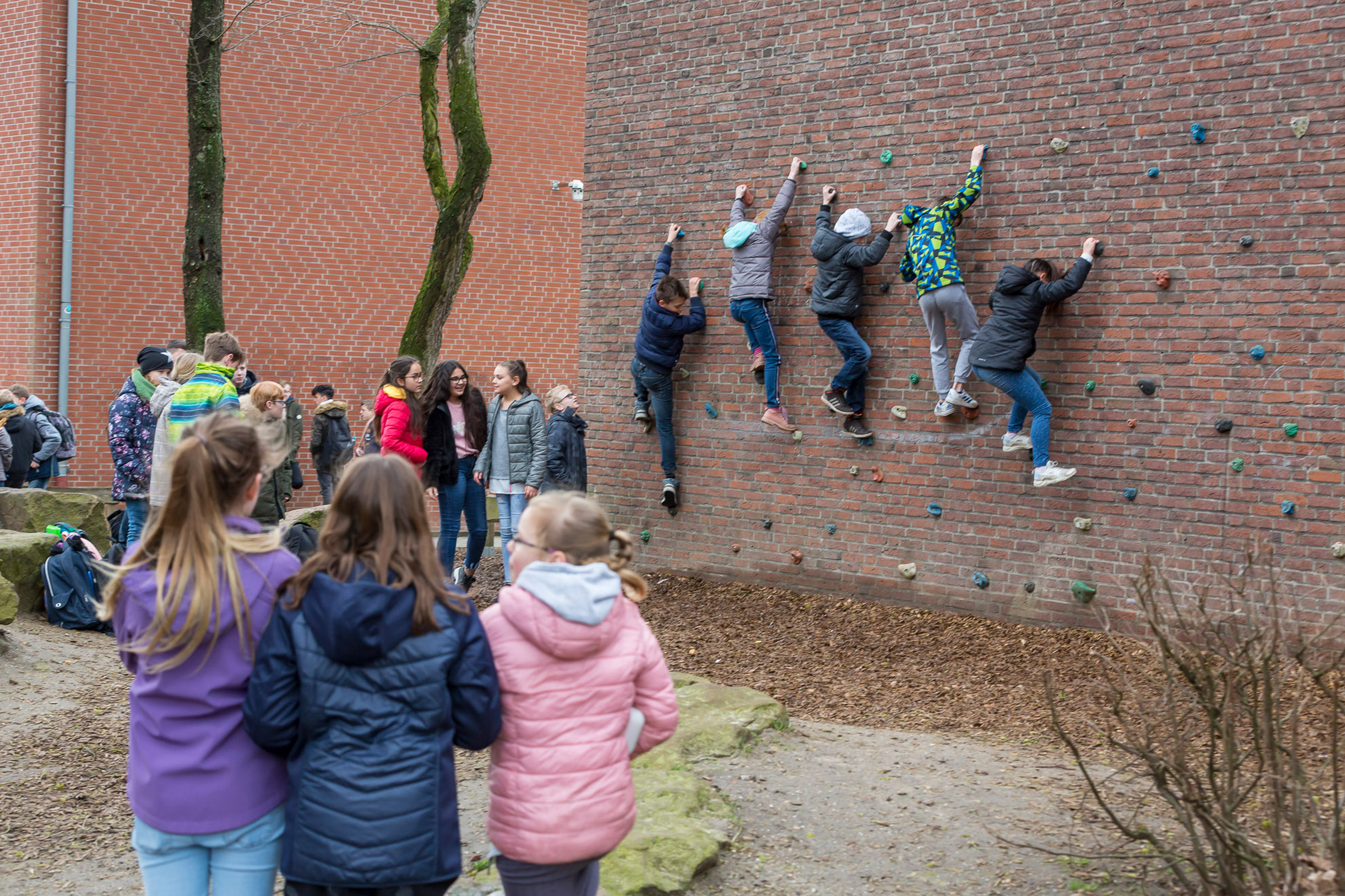 Kinder auf dem Schulhof an einer Kletterwand