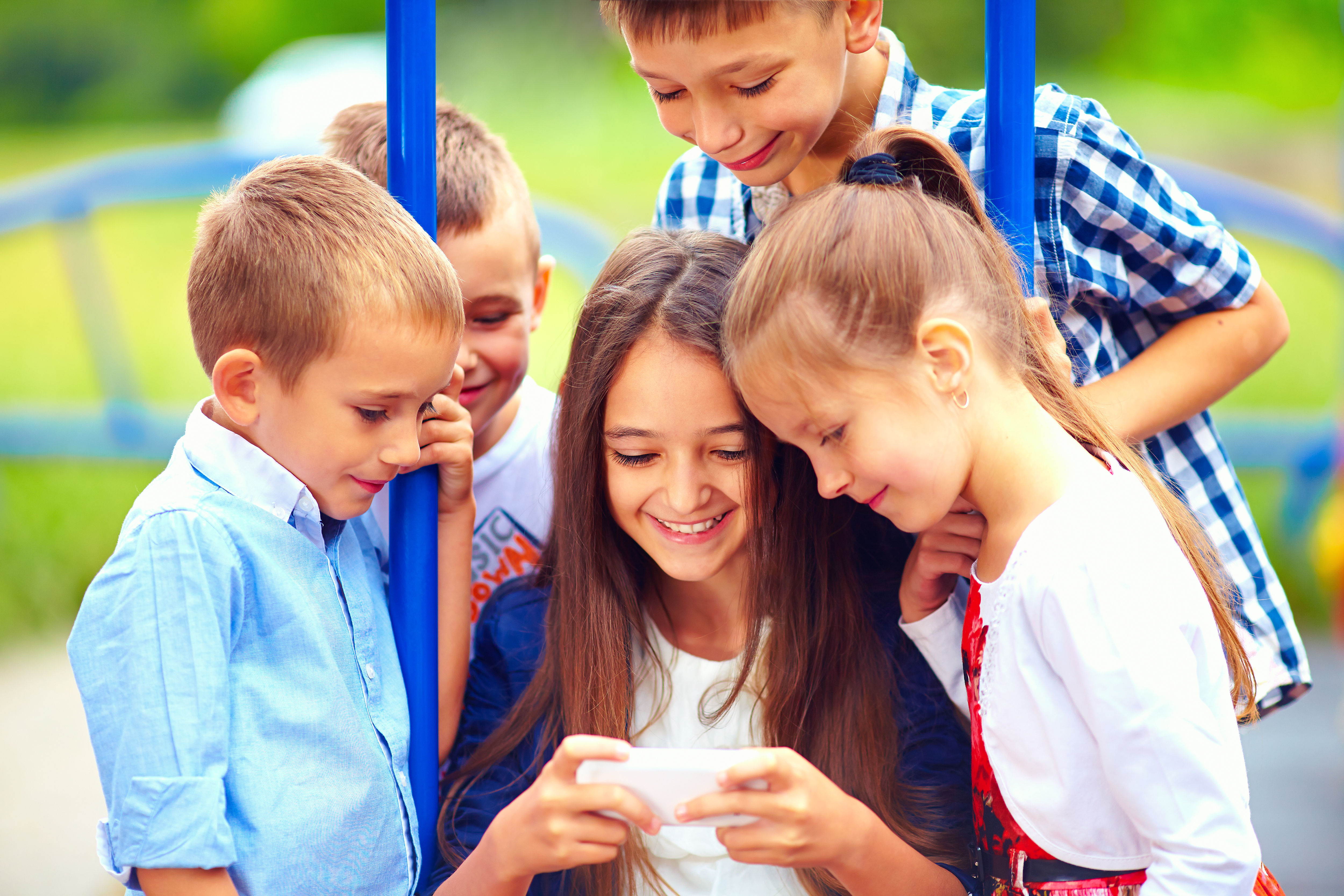 Eine Gruppe von Kindern schaut auf ein Handy