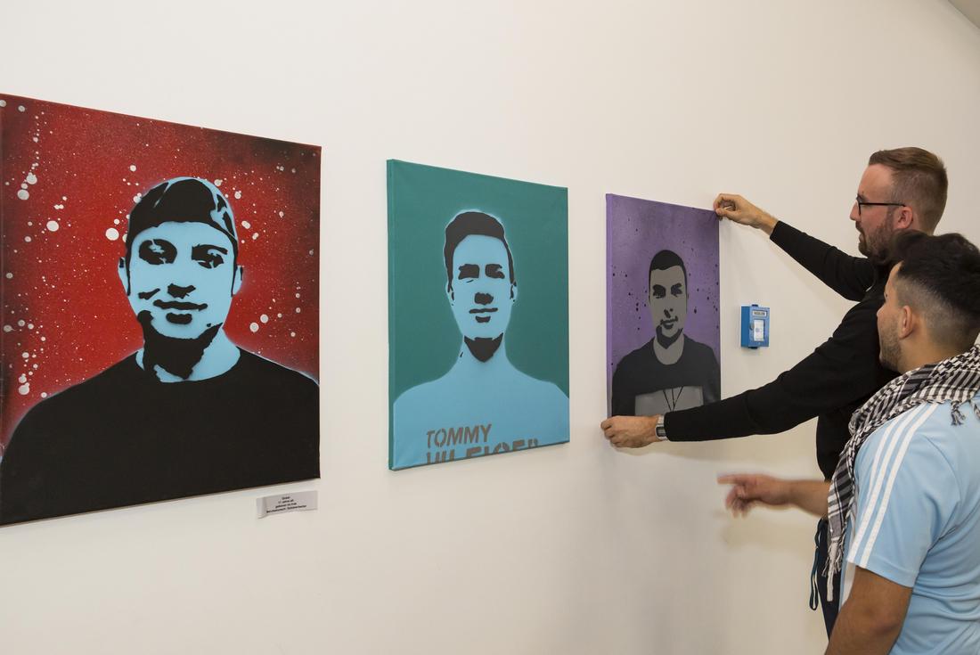 Ein Mann hängt Bilder auf