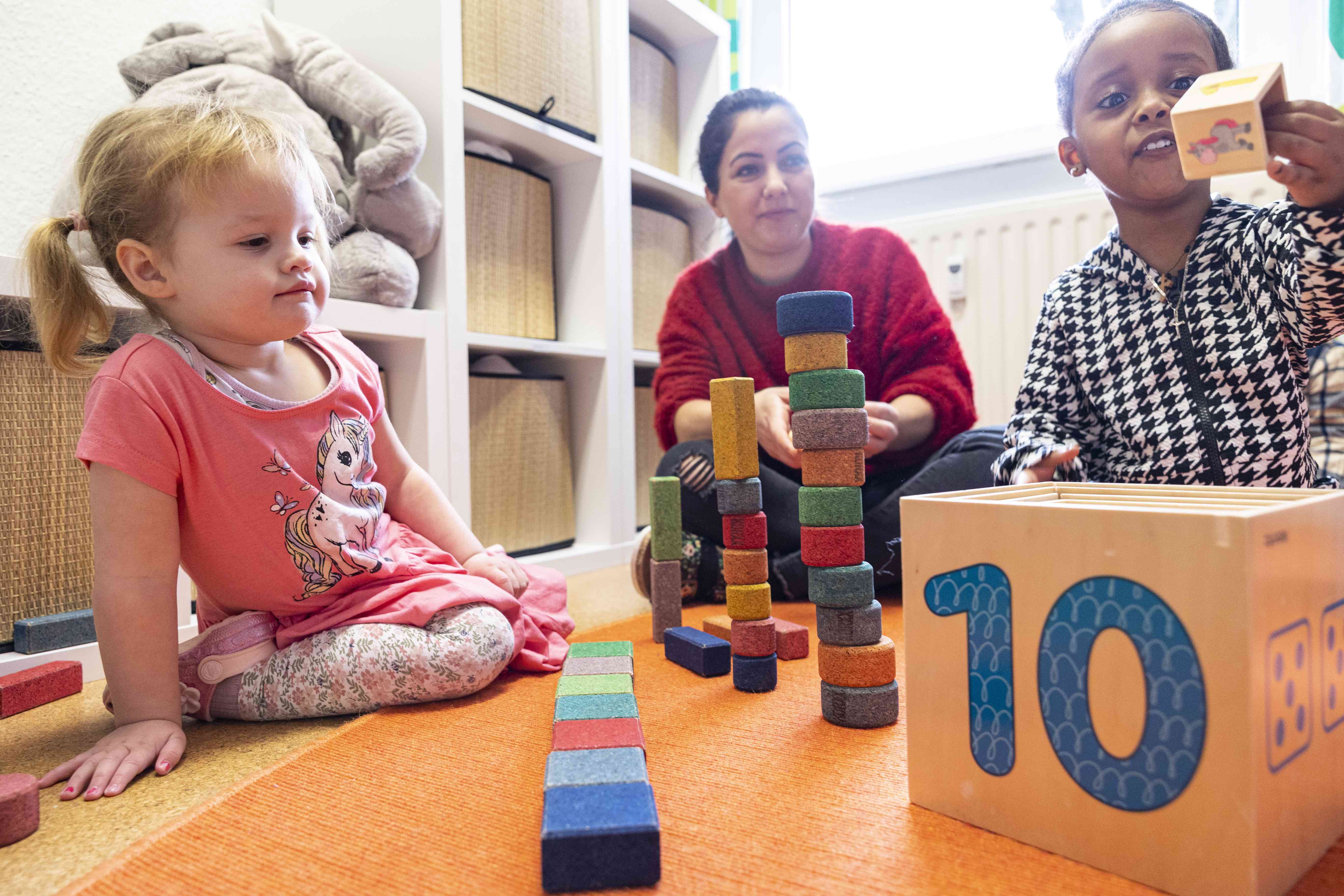 2 Kinder und eine Erzieherin spielen mit Bausteinen