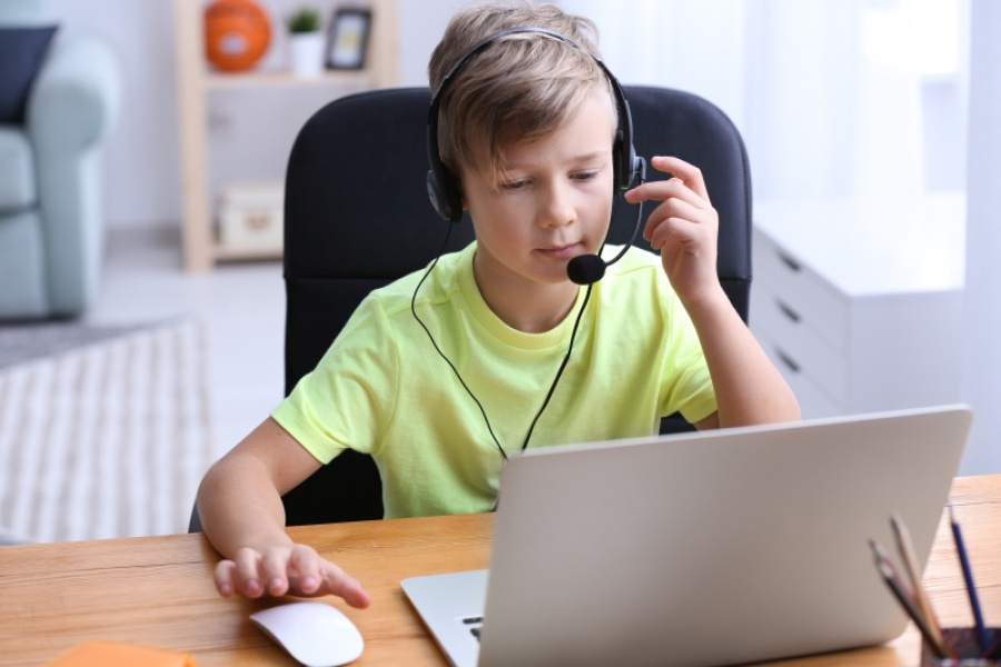 Junge mit Headset am Laptop sitzend