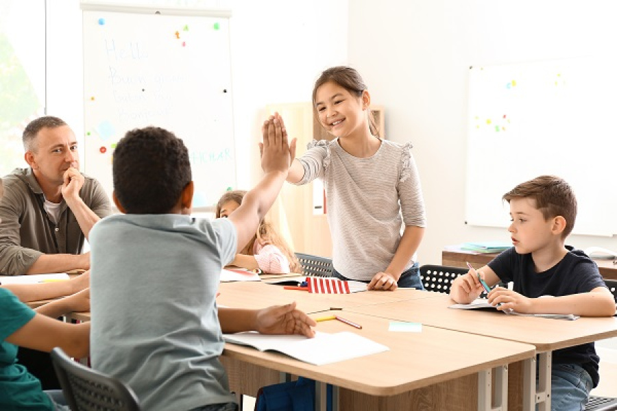 Schüler*innen an einem Tischen, die sich High Fiven