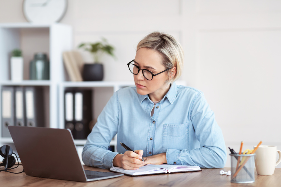 Am Laptop sitzende Frau, die sich Notuzen macht