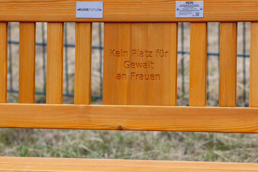 Detailansicht der orangefarbenen Bank mit RuhrFutur-Logo und Aufschrift "Kein Platz für Gewalt an Frauen"
