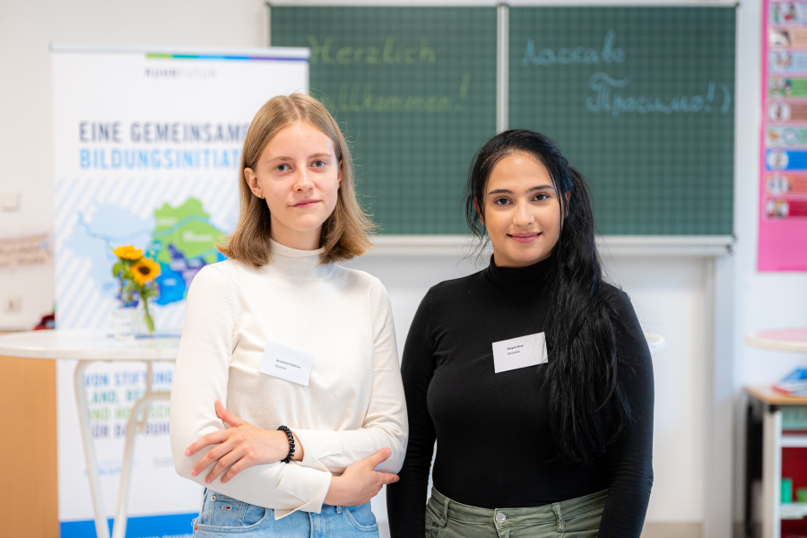 Zwei Frauen, eine blind und eine schwarzhaarig, stehen in einem Klassenraum