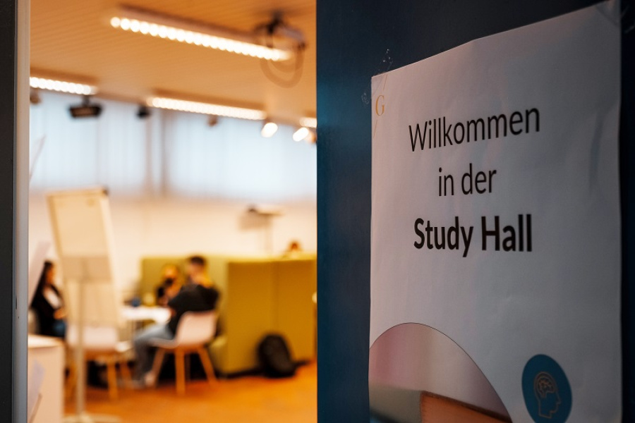 Zettel auf Tür mit Aufschrift: Willkommen in der Study Hall; Im Hintergrund: Drei Personen sitzen an einem Tisch