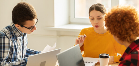 Drei junge Menschen am Laptop diskutieren