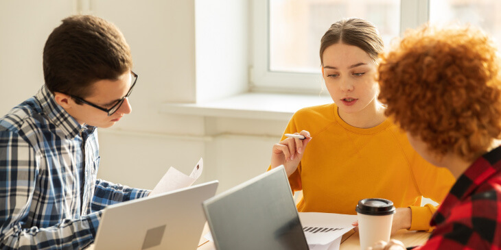Drei junge Menschen am Laptop diskutieren