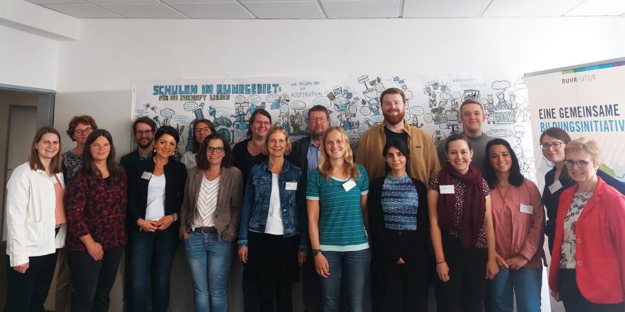 Die Teilnehmer*innen des Netzwerkstreffens Frühkindliche Bildung und Schule stehen nebeneinander und blicken in die Kamera