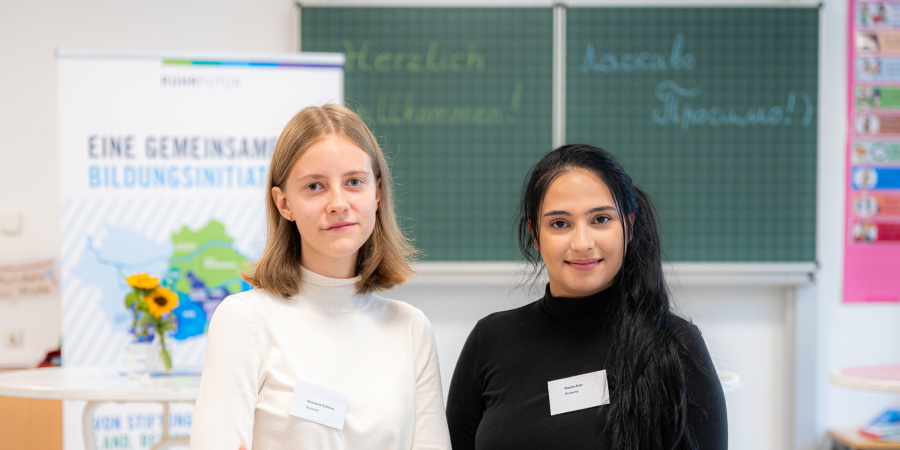 Zwei Frauen, eine blind und eine schwarzhaarig, stehen in einem Klassenraum