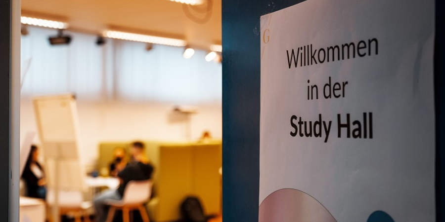 Zettel auf Tür mit Aufschrift: Willkommen in der Study Hall; Im Hintergrund: Drei Personen sitzen an einem Tisch