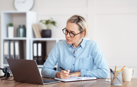 Am Laptop sitzende Frau, die sich Notuzen macht